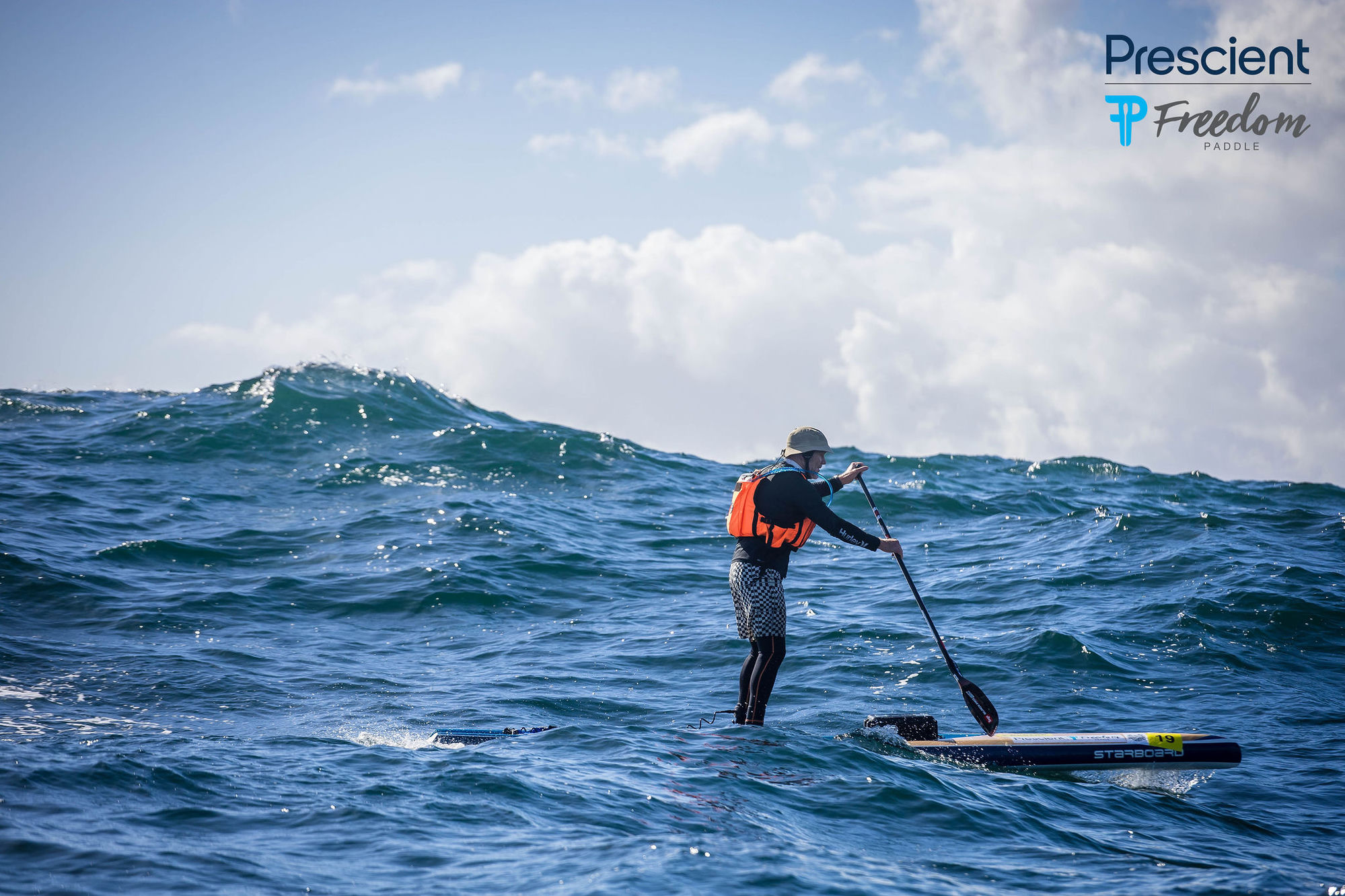 Brian Roberts on his Starboard SUP with a massive swell rising behind him at the 2026 Prescient Freedom Paddle